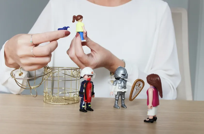 Manos colocando figuras de Playmobil, una herramienta de la terapia
